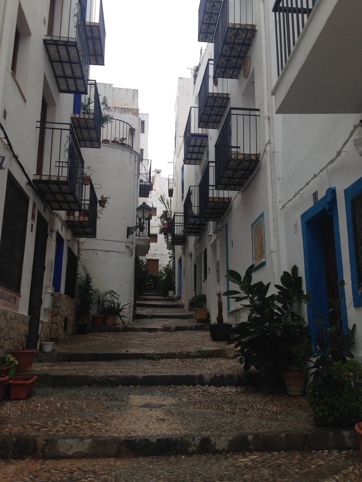 Narrow street with white buildings and stairs.
