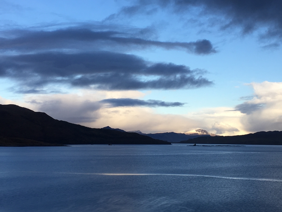 Étendue d'eau calme avec des montagnes au loin pendant le crépuscule.