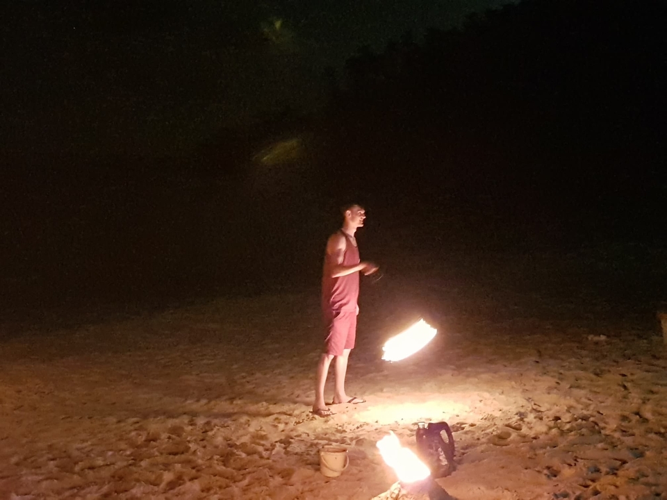 Personne exécutant une danse du feu sur une plage la nuit.