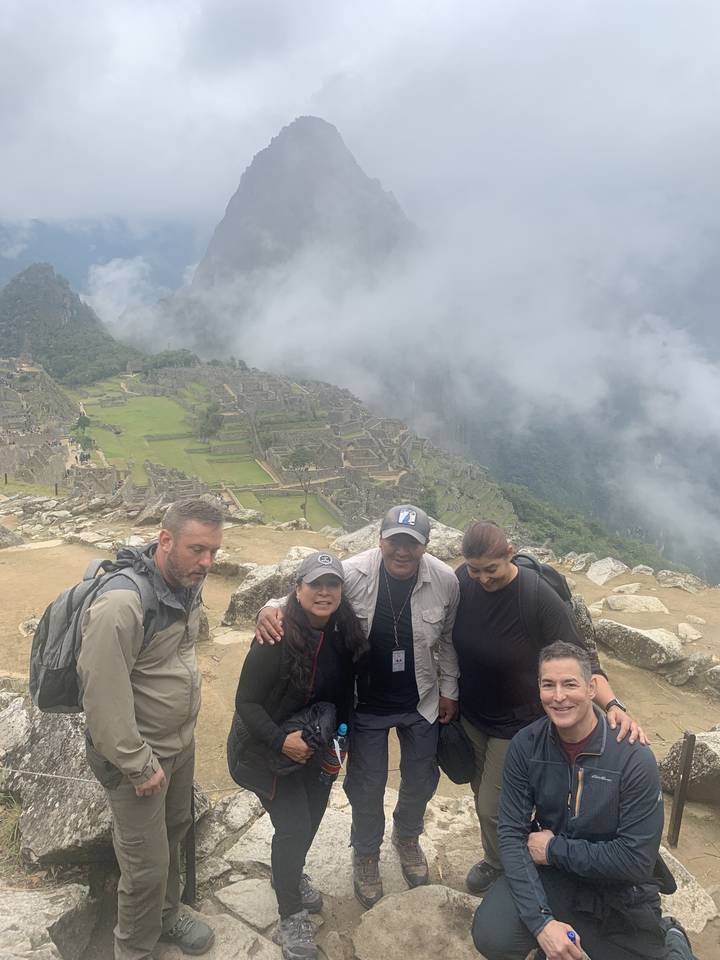 Un groupe de personnes posant sur un sentier avec une montagne derrière.