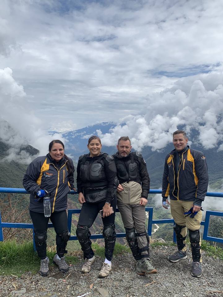 Quatre personnes posant en équipement d'aventure avec vue sur un paysage pittoresque.