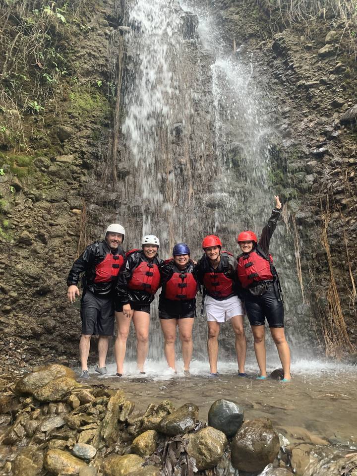 Groupe de personnes en gilets de sauvetage posant sous une cascade.