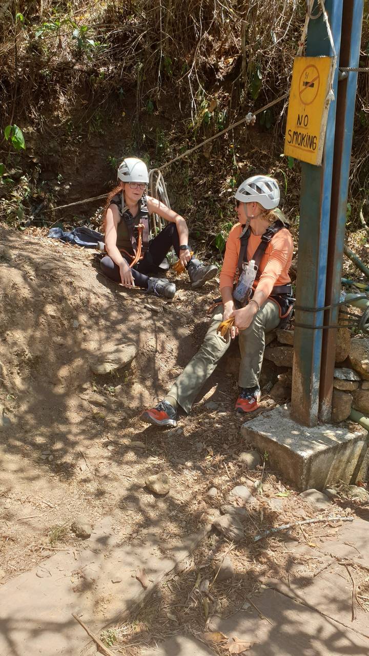 Deux personnes se reposant près d'un panneau d'interdiction de fumer avec des casques.