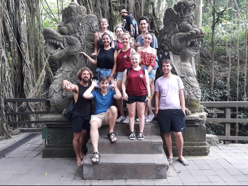 Group of people posing on ancient steps with carved statues.