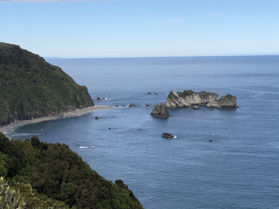 Vue côtière avec affleurements rocheux et océan bleu.