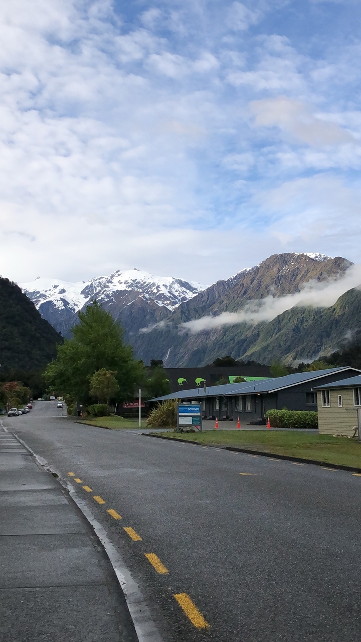 Montagnes brumeuses avec des sommets enneigés et une zone forestière.
