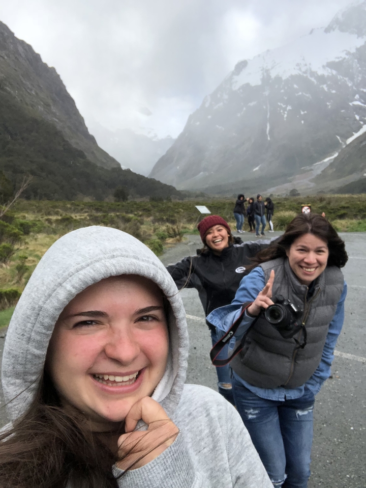 Des amis prenant un selfie avec un paysage de montagnes brumeuses en arrière-plan.