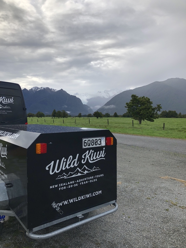 Fourgon de tournée « Wild Kiwi » garé avec des montagnes visibles en arrière-plan.