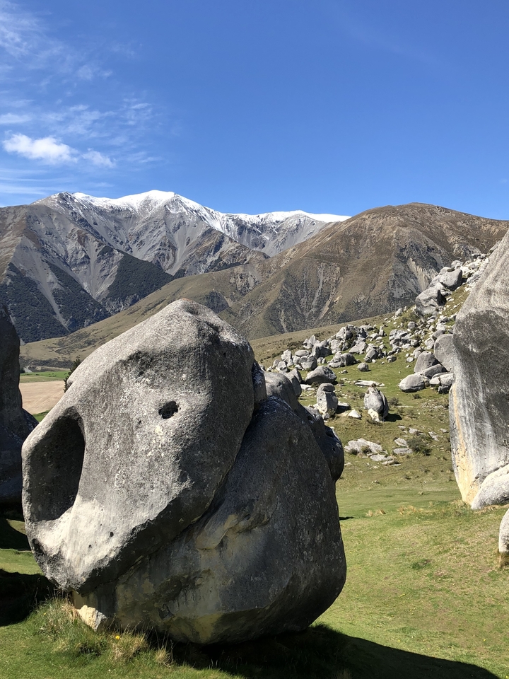 Mountain landscape with rocky formations and distant snow-capped peaks.