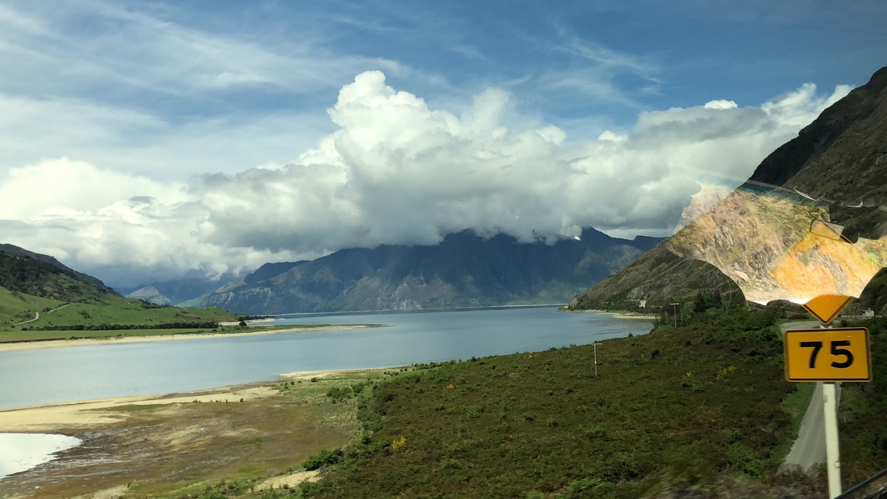Vue du lac avec ciel nuageux et montagnes.