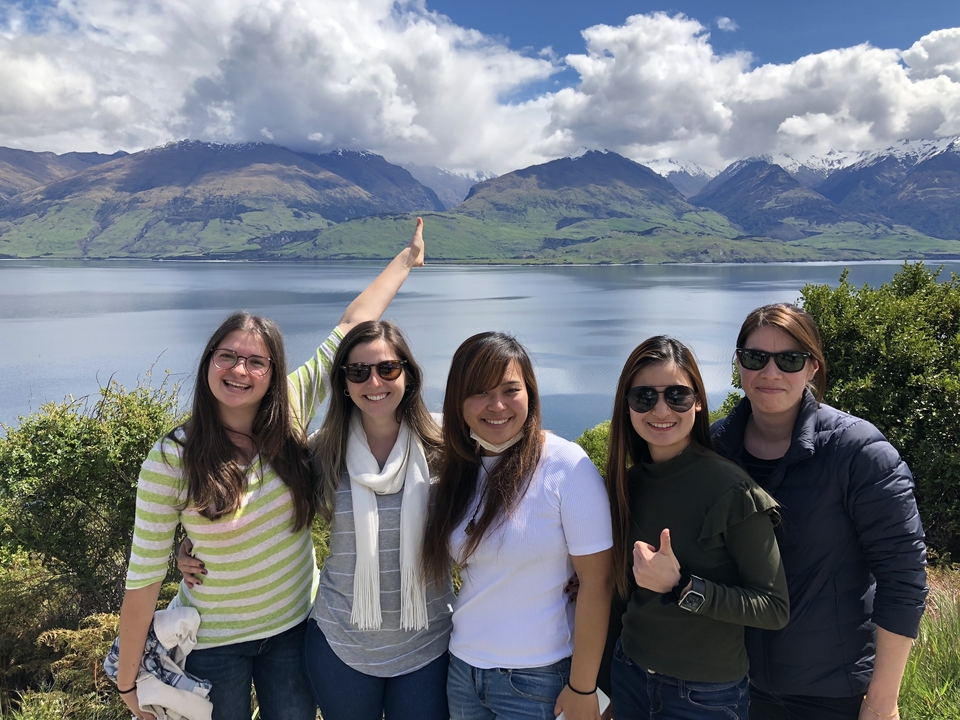 Un groupe d'amis qui posent avec des montagnes et de l'eau en arrière-plan.
