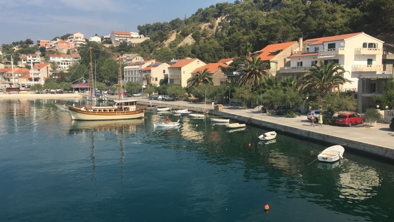 Petit village côtier avec des bateaux amarrés le long d'une voie navigable calme.