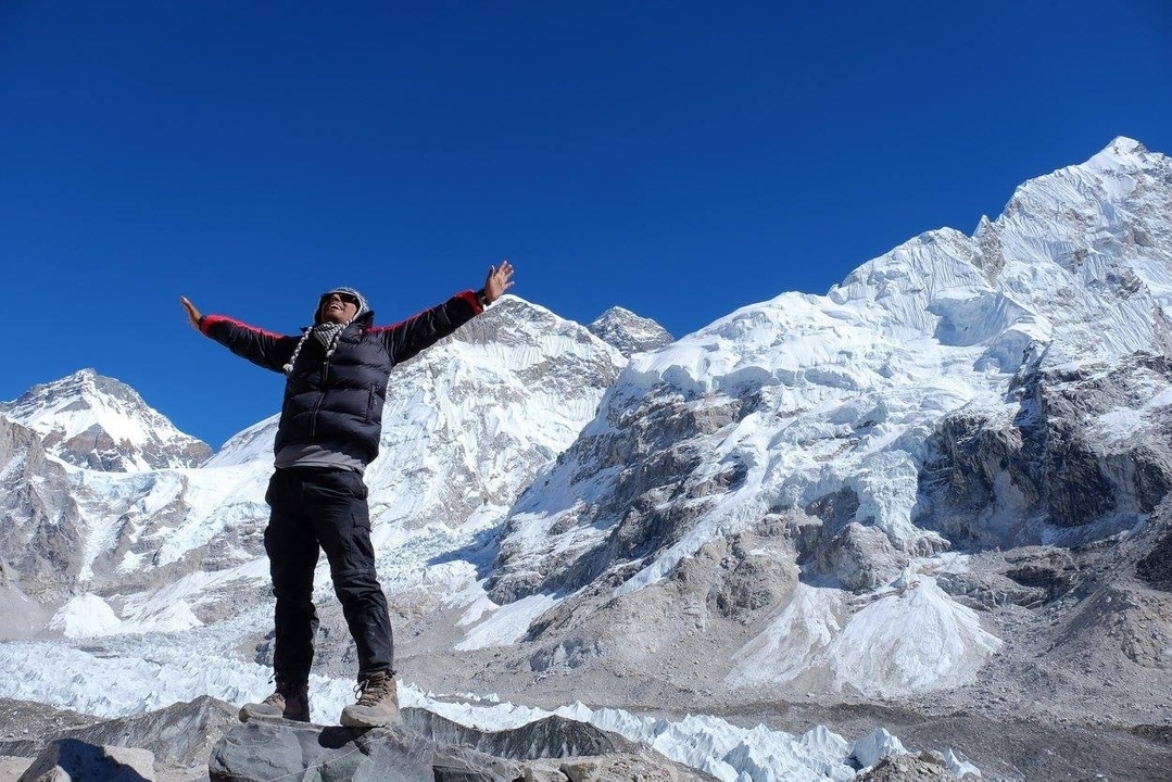 Personne posant triomphalement devant des montagnes enneigées au Népal.