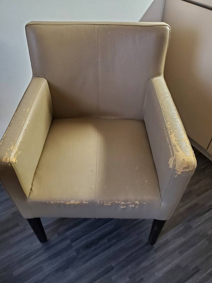 Fauteuil usé avec un revêtement qui s'écaille.