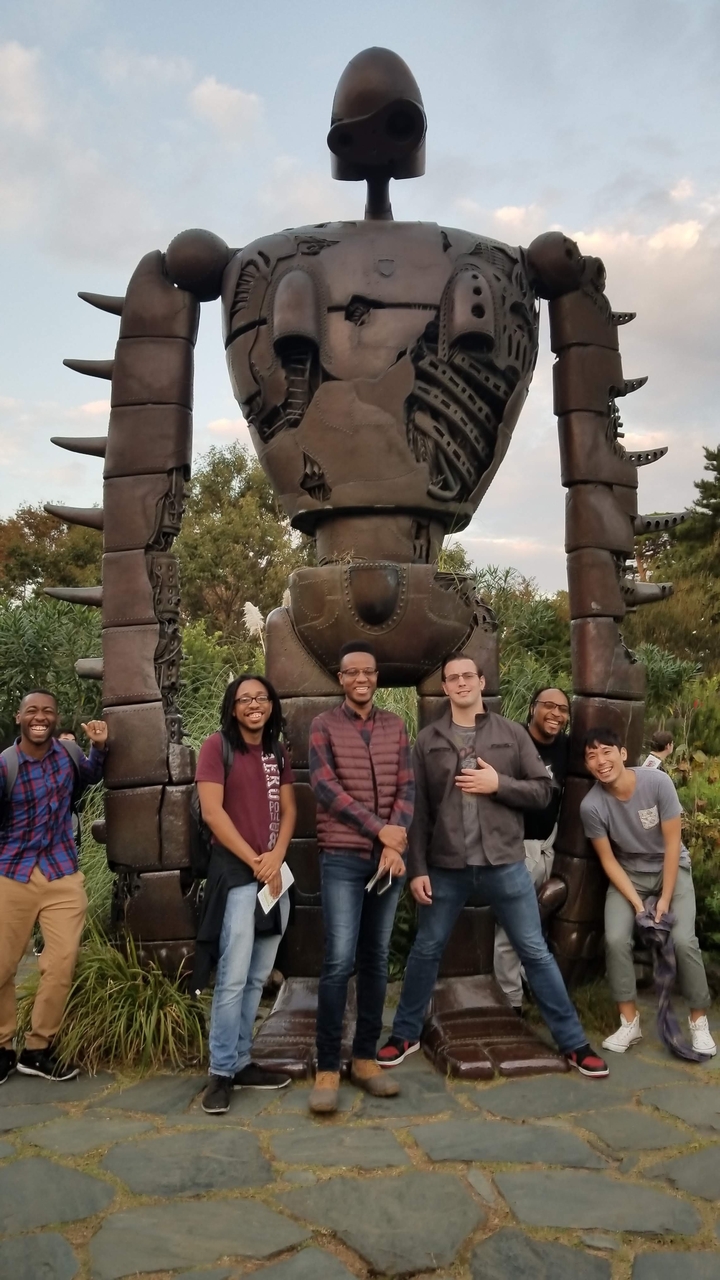 Groupe d'amis debout devant une sculpture de robot