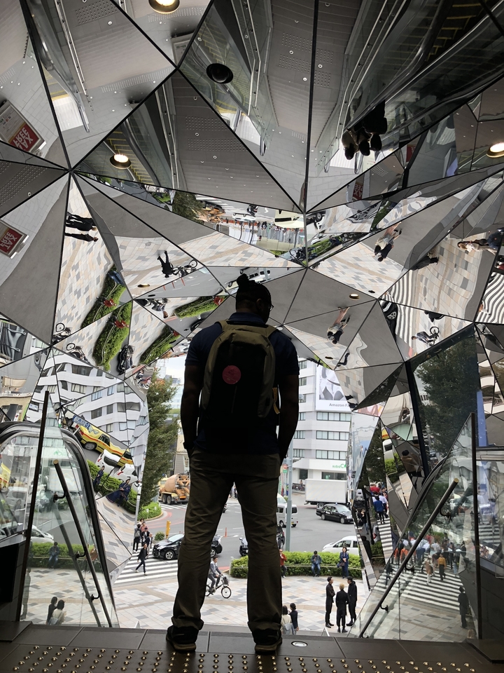 Personne devant une structure en miroir reflétant des scènes extérieures.