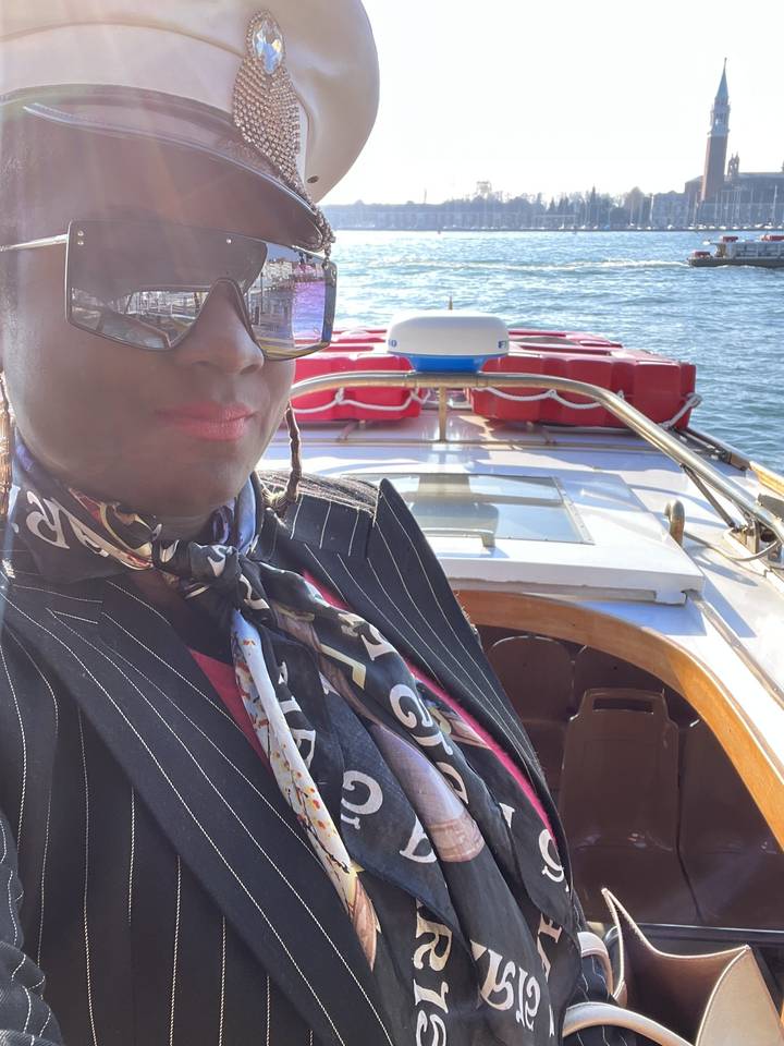 Personne portant des lunettes de soleil sur un bateau, avec de l'eau en arrière-plan.