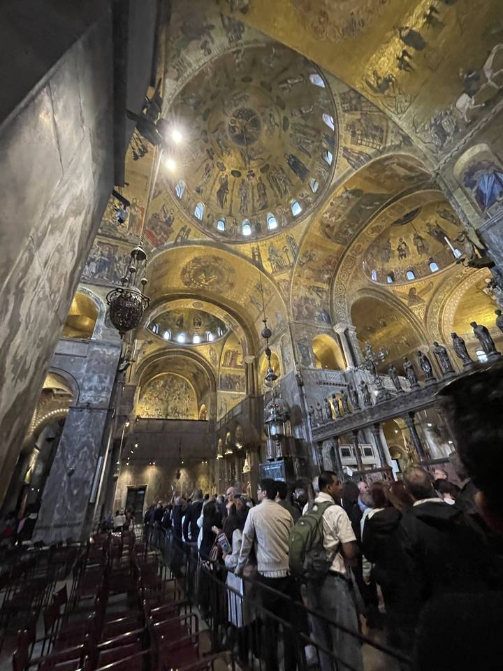 Intérieur d'une cathédrale dorée avec des visiteurs.