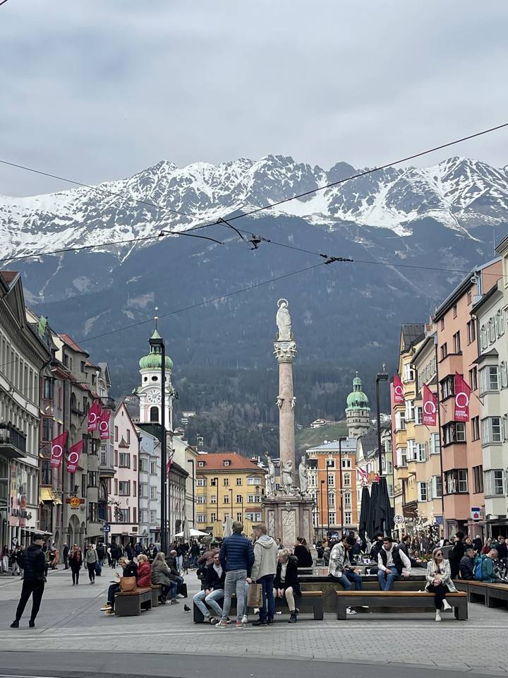 Des gens assis sur une place avec des montagnes en arrière-plan.