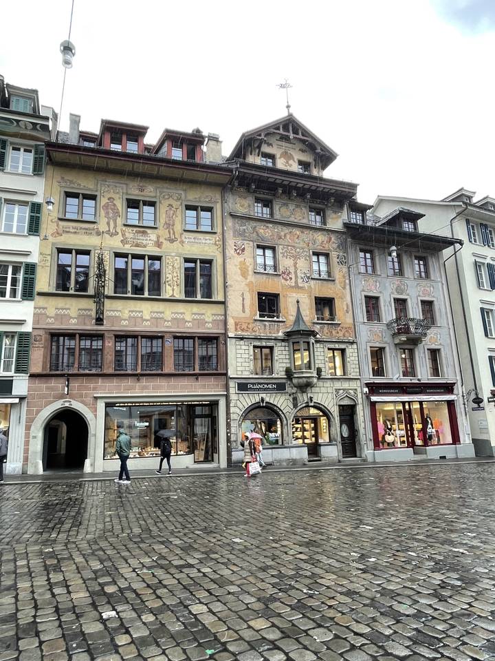 Des gens devant des bâtiments historiques richement décorés sur une place de ville.