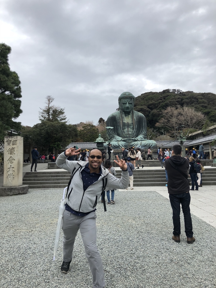 Personne posant avec un signe de paix devant le Grand Bouddha.