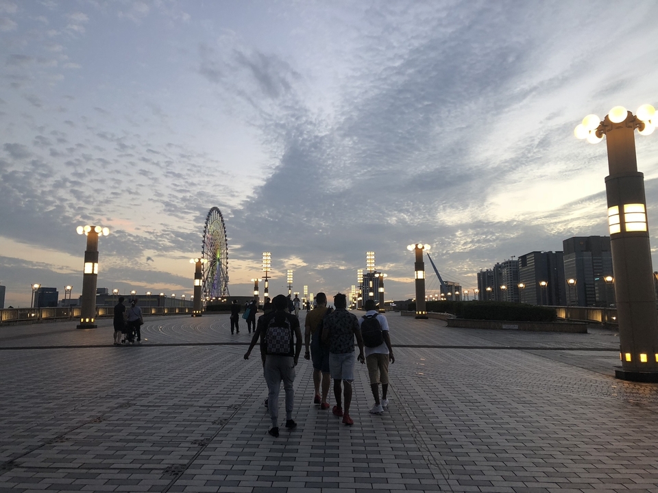 Des gens qui marchent vers un coucher de soleil avec une grande roue au loin.