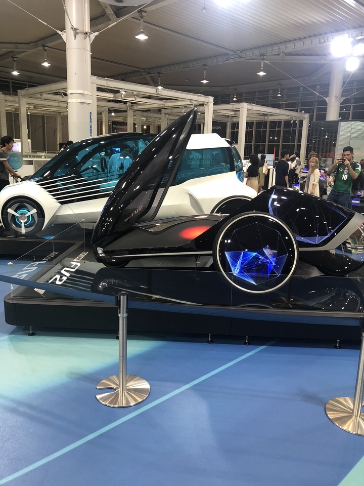 Des gens explorent des voitures conceptuelles futuristes dans une exposition.