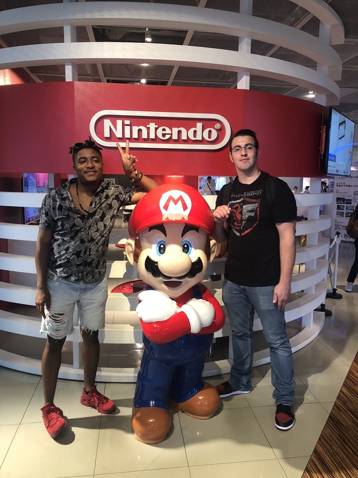 Deux personnes posant avec une statue de Mario de Nintendo.