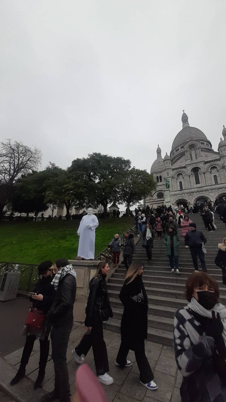 Des gens se sont rassemblés près d'un grand bâtiment à coupole avec des escaliers.