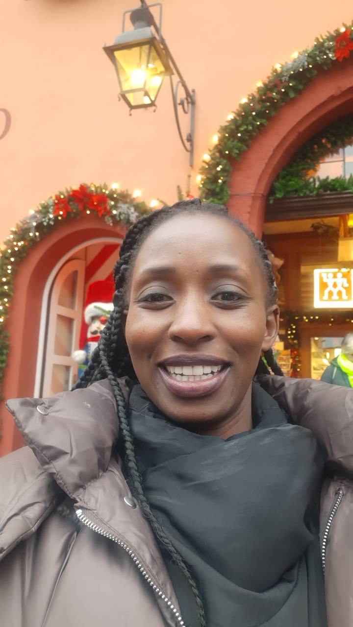 Personne souriante devant un bâtiment décoré de façon festive.