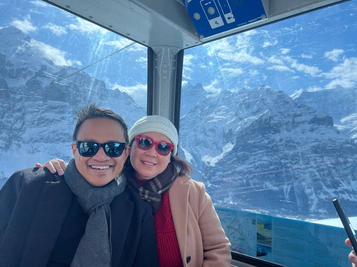 Deux personnes posant dans un paysage enneigé vu à travers une vitre.