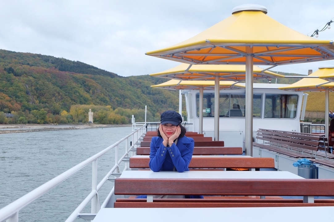 Personne qui pose sur le pont d'un bateau de croisière avec vue sur la rivière.