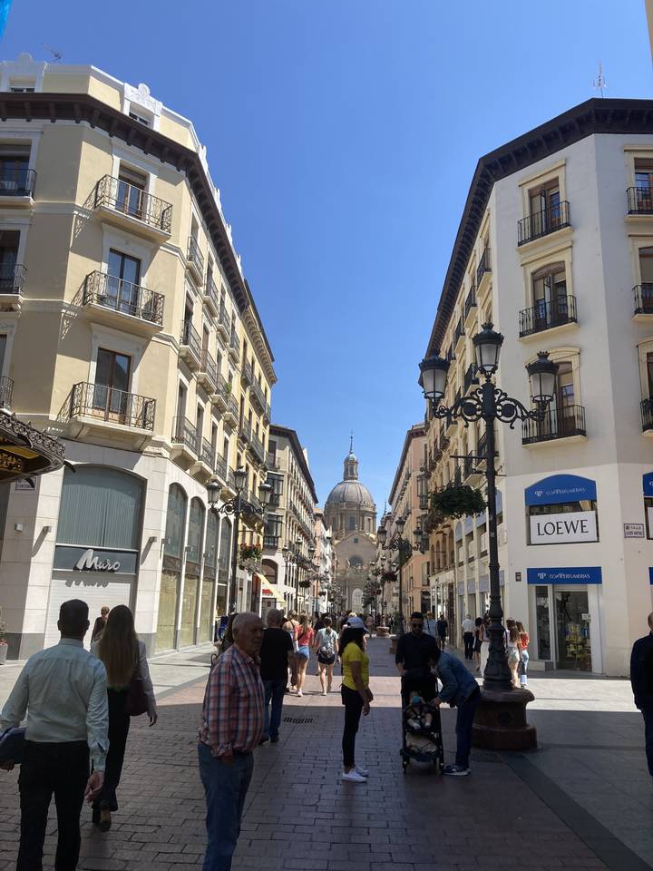 Rue animée avec un bâtiment à coupole au loin.
