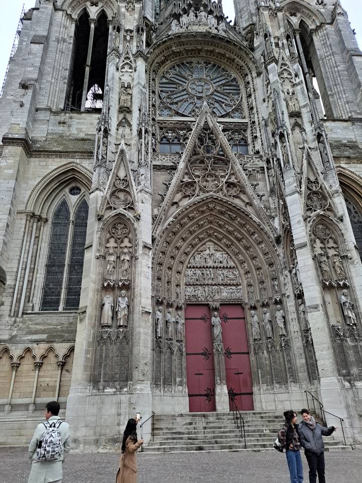 Des gens prennent des selfies dans une cathédrale à l'architecture ornée.