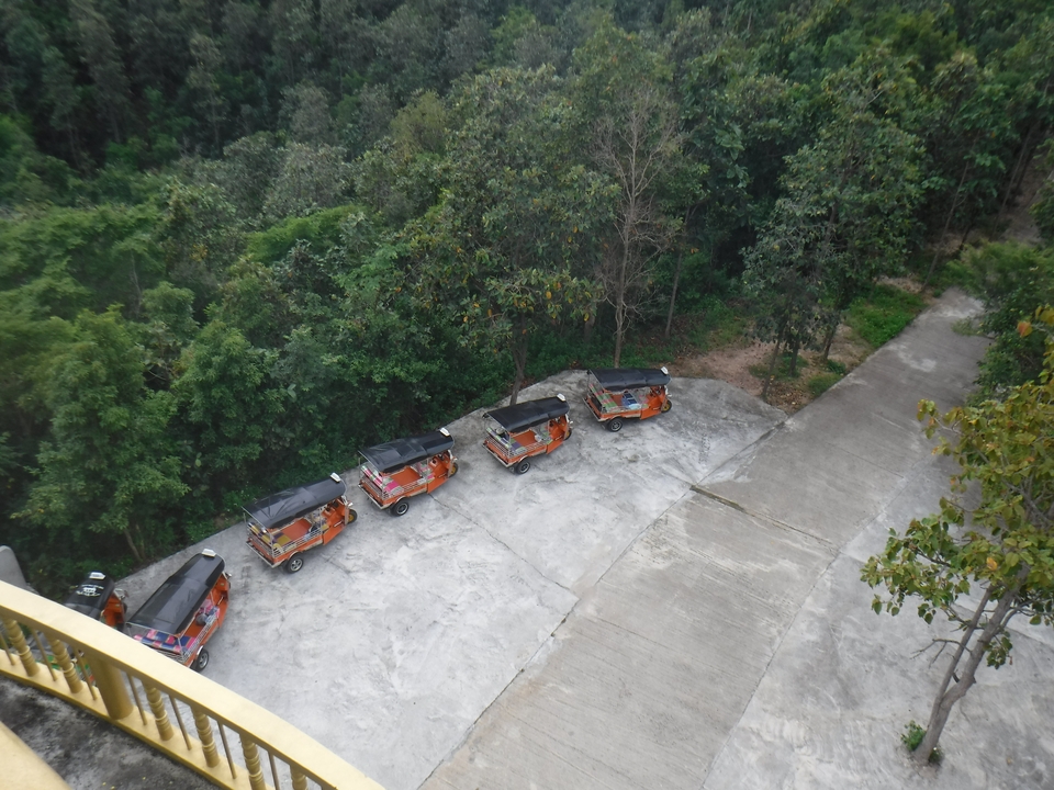Cinq tuk-tuks garés sur une colline boisée.