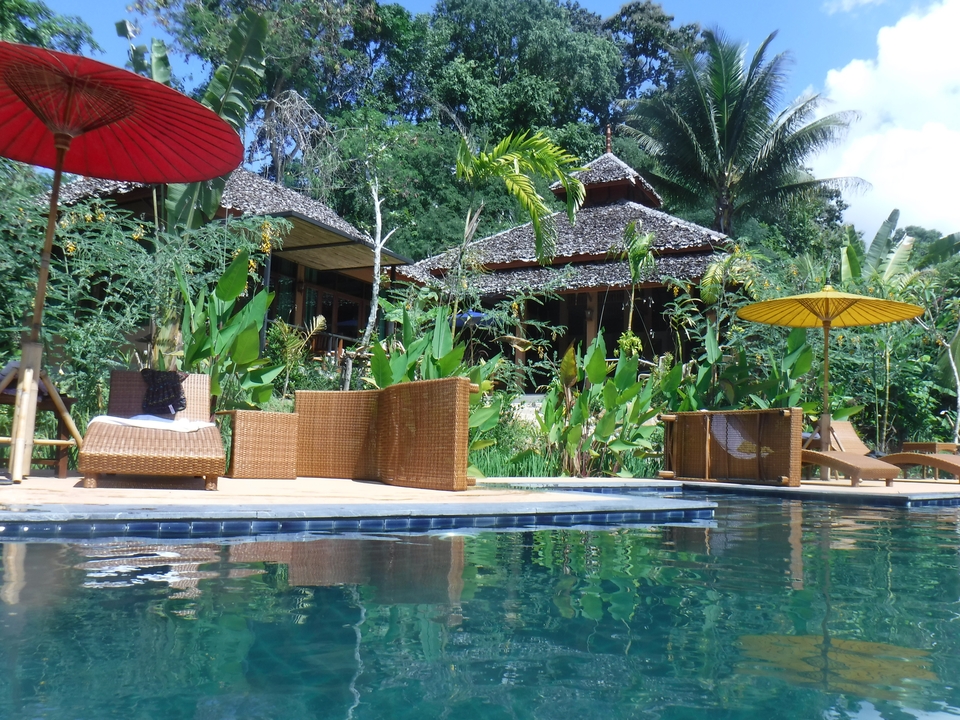 Station balnéaire tropicale avec piscine et végétation.