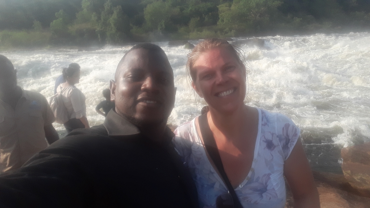 Deux personnes souriantes avec une cascade en arrière-plan.
