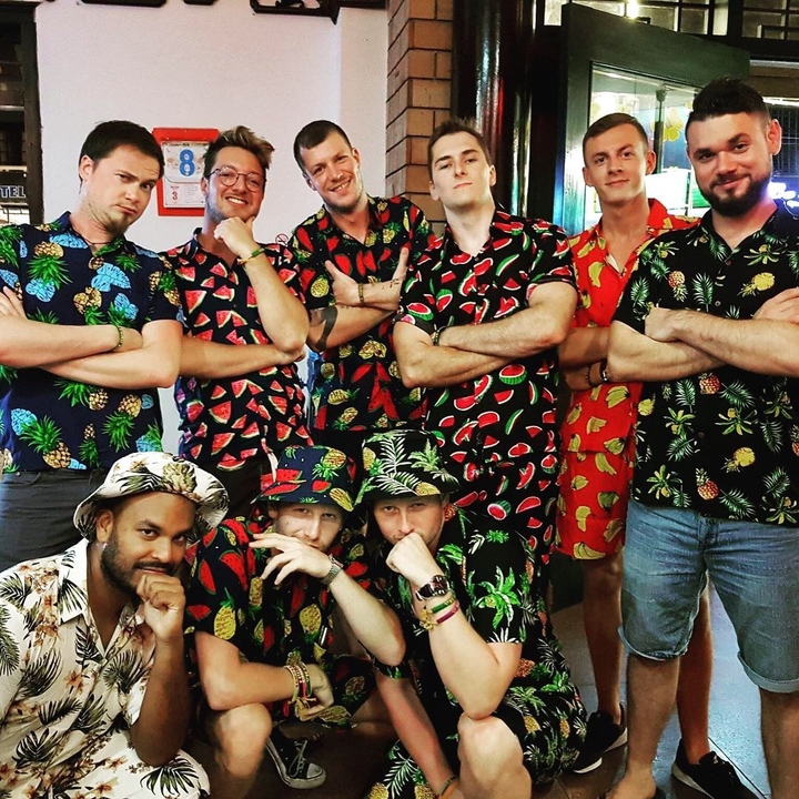 Group of people wearing colorful, themed shirts.