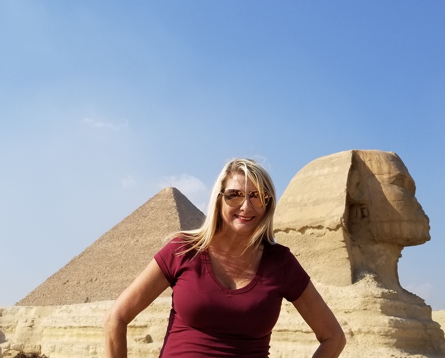 Une personne devant le Sphinx et une pyramide.