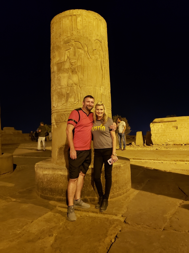 Deux personnes posant avec des sculptures en pierre historiques.
