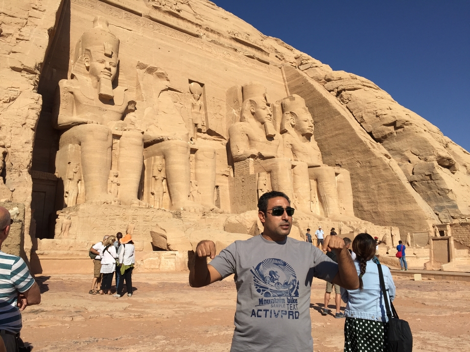 Une personne qui fait des gestes devant les temples d'Abou Simbel.