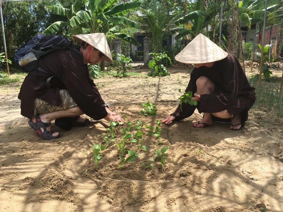 Deux personnes qui plantent dans un jardin portant des chapeaux traditionnels.