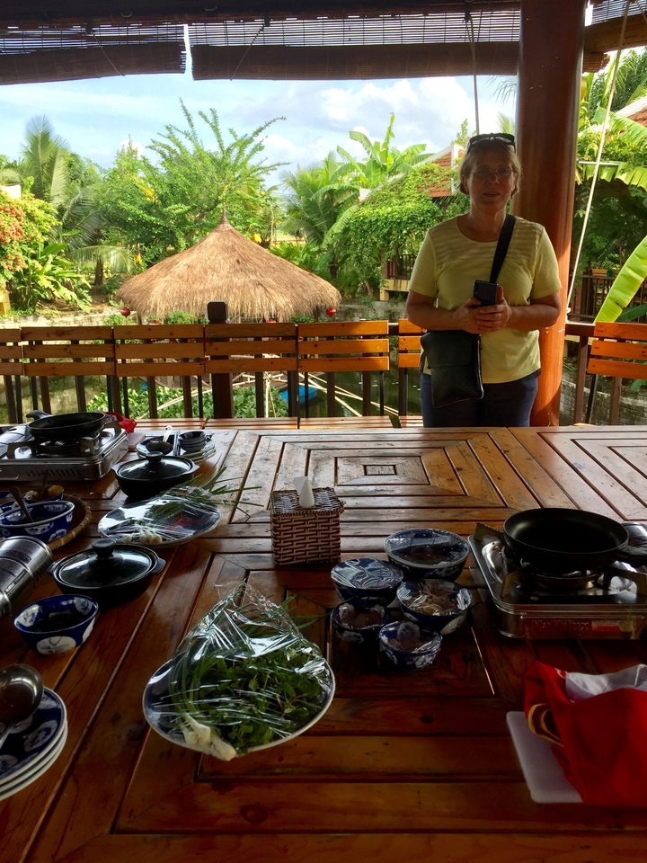 Zone de restauration avec une table en bois dressée pour un repas, homme debout avec un sac sur l'épaule.