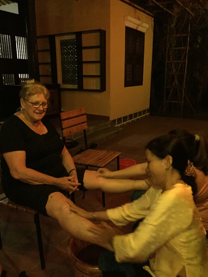 Deux femmes assises, profitant d'une soirée, l'une d'elles recevant un massage des pieds.