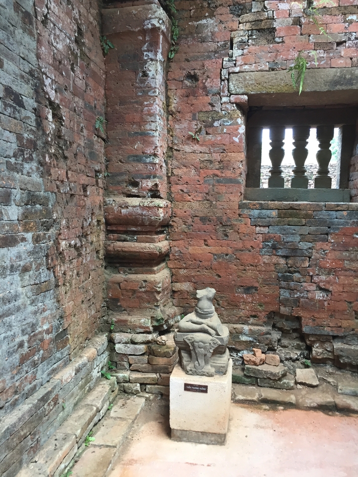 Ancienne structure en brique avec une petite statue.