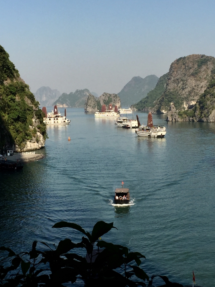 Vue panoramique de la baie d'Halong avec des bateaux et des formations karstiques calcaires.