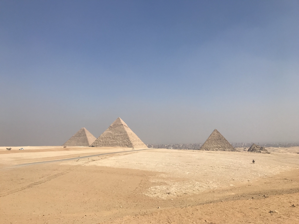 Vue large des pyramides dans un décor désertique.