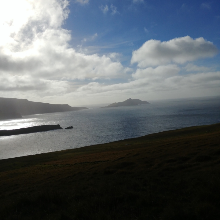 Paysage côtier avec ciel nuageux et îles au loin.