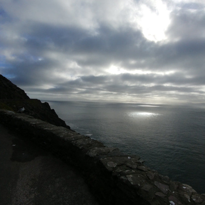 Paysage marin nuageux avec la lumière du soleil se reflétant sur l'eau.