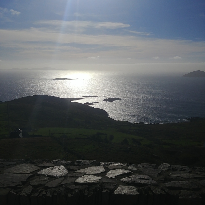 Vue panoramique de l'océan avec la lumière du soleil se reflétant sur l'eau et de petites îles au loin.